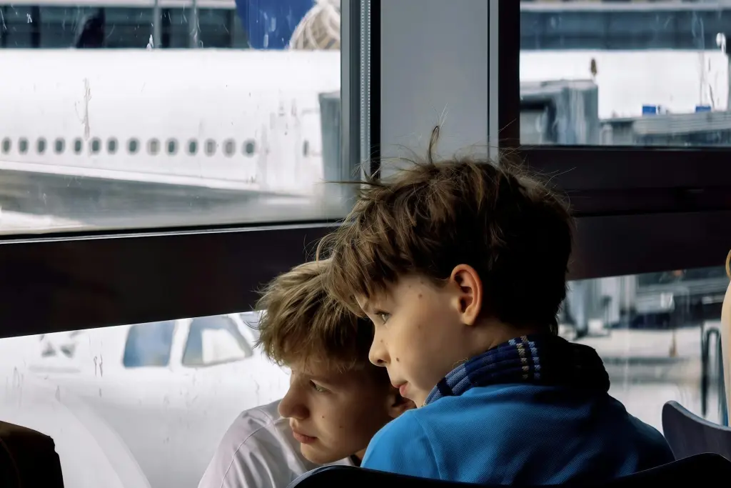 Deux garçons regardent les avions de ligne par la fenêtre de l'aéroport