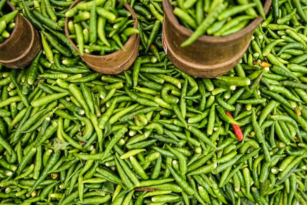 Piments verts en vrac et dans des paniers sur un étal