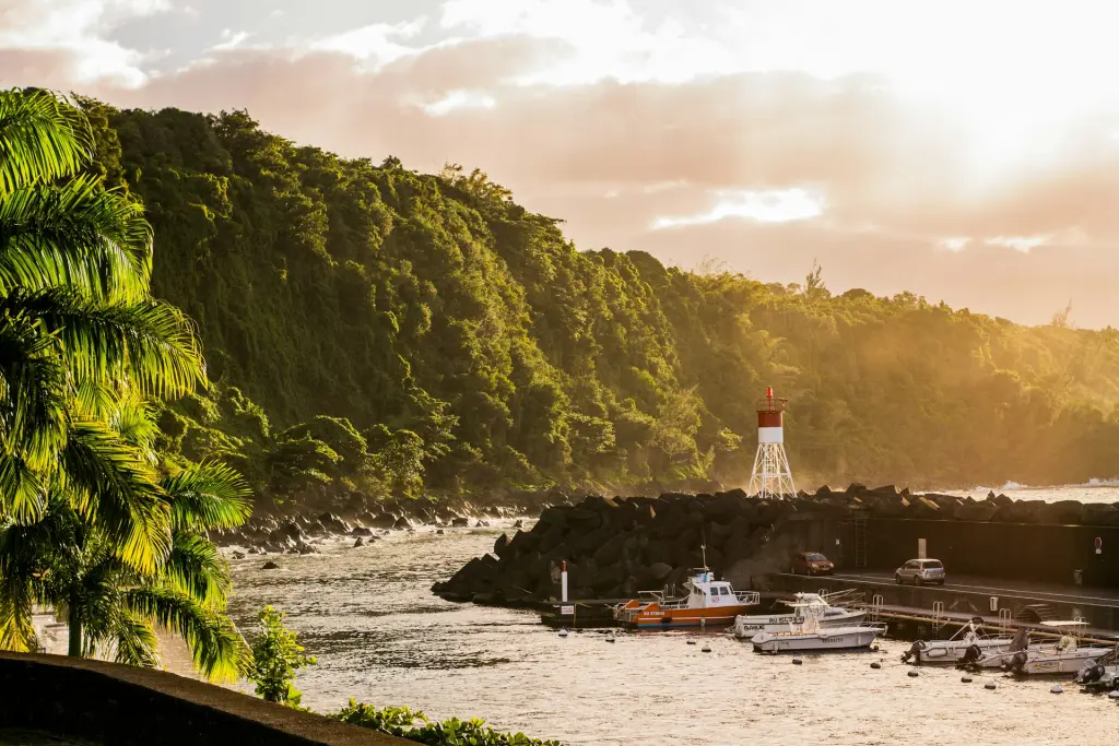 Petit port avec un phare rouge et blanc au soleil couchant